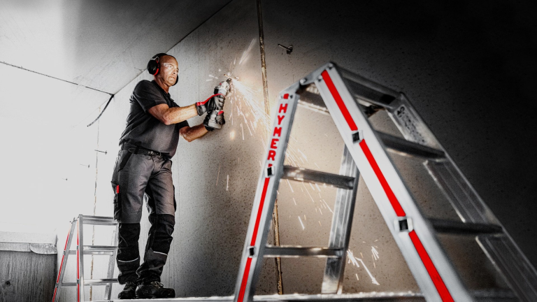 Monteur op aluminium Hymer ladder aan gevel van woning