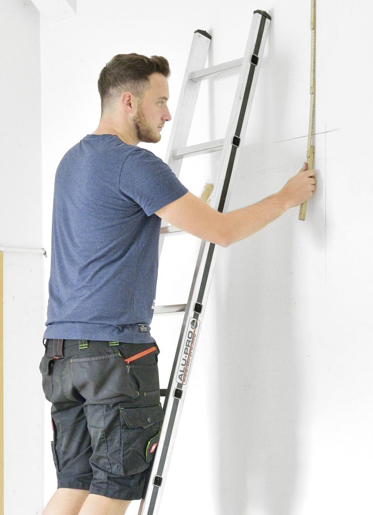Man gebruikt Alu-Pro Ladder 70011 tijdens installatiewerk aan muur, aluminium ladder met antislip sporten