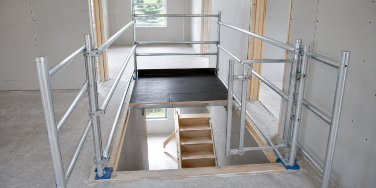 Trapgat steiger met werkplatform en leuningen voor veilig werken boven een open trapgat.